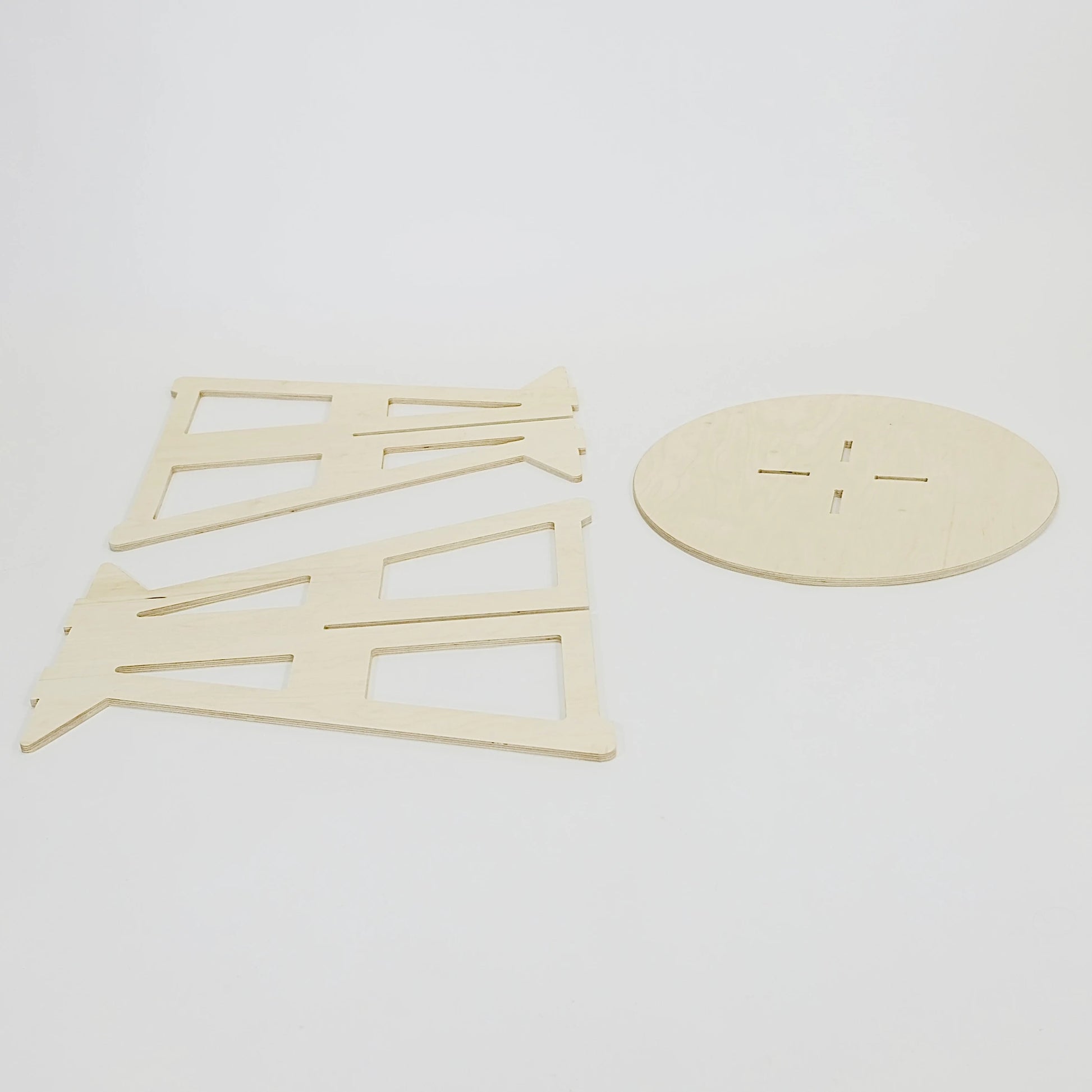 Flat lay of the table separated into its component parts. The wood is pale coloured. The top is round and the two legs are triangle shaped.