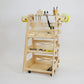 Tall birch plywood tool trolley with 3 shelving tray, multiple tool storage slots with hammer, mallet, sandpaper roll & various tools stored in purpose cut holes standing at an angle facing to the left against a white background.
