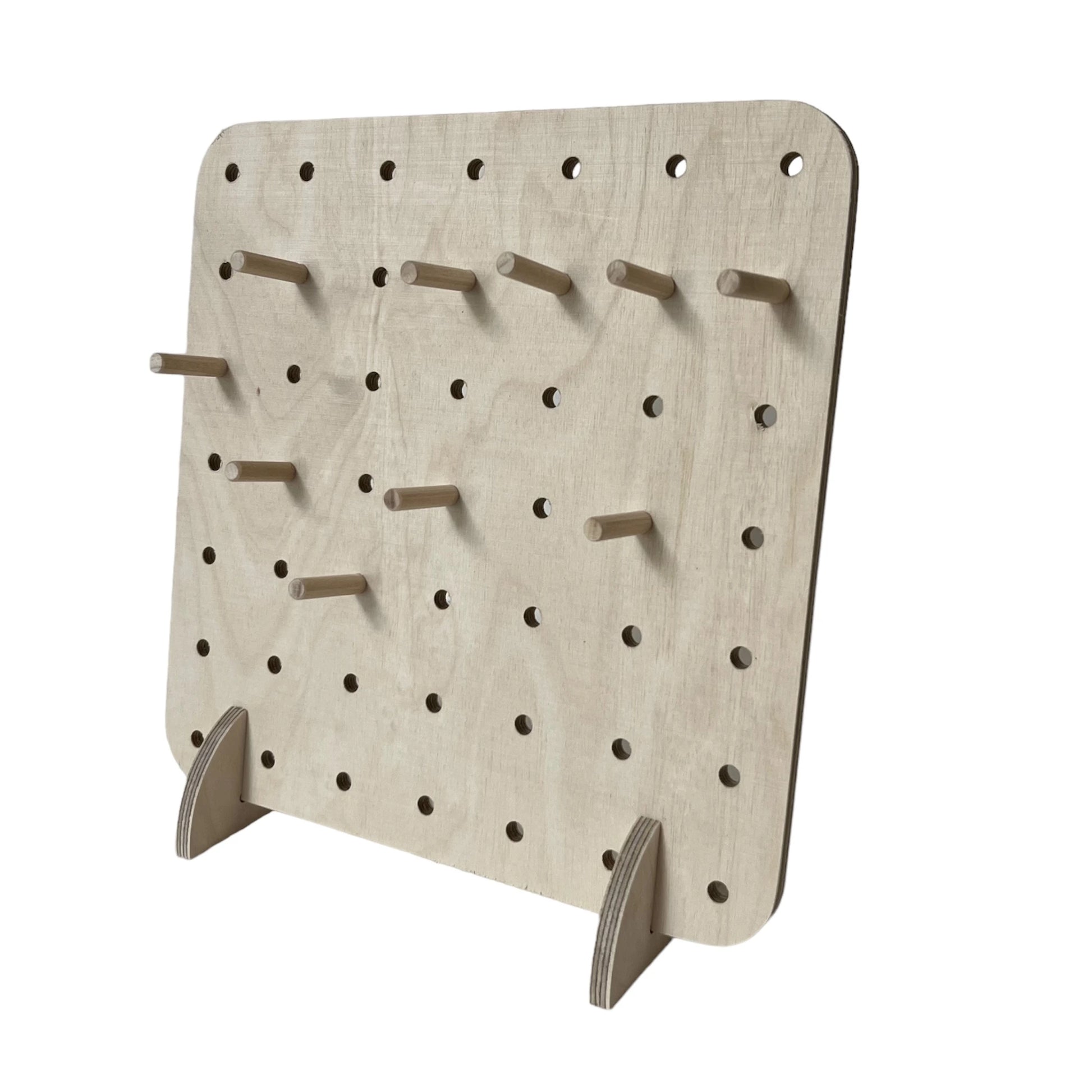 Pale wooden square pegboard with small 6mm drilled holes and some pegs facing to left