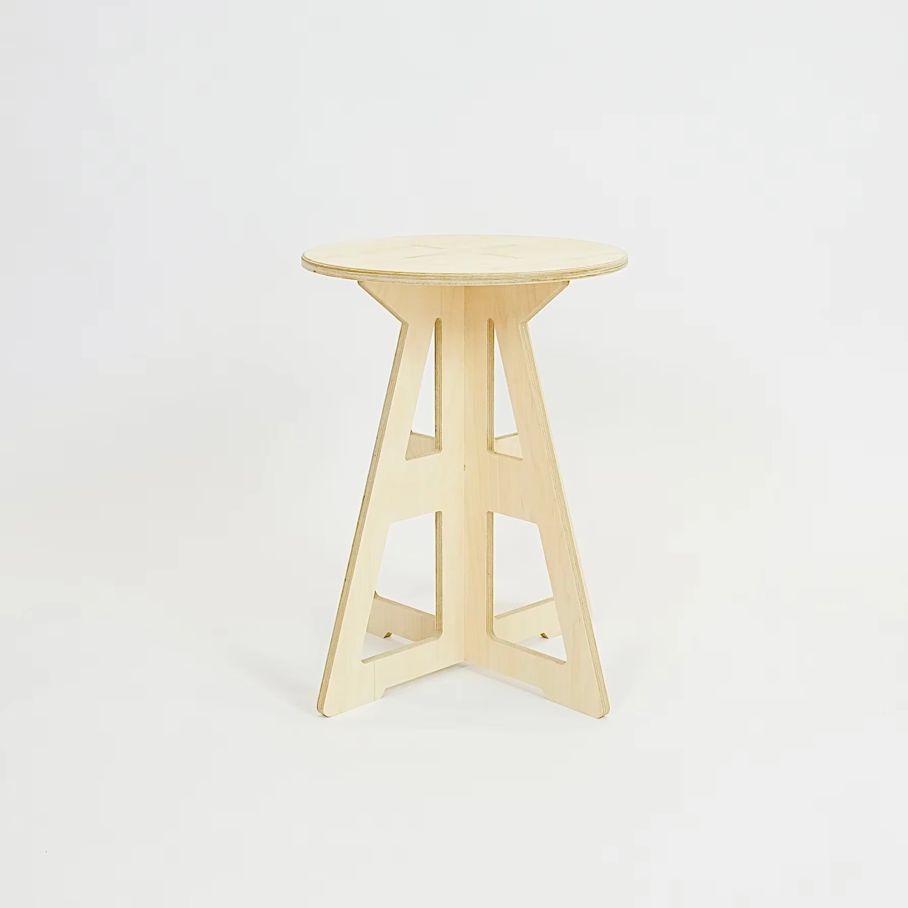 A simple modern pale wooden small stool. It has a round top and triangle legs which are slotted together in a cross shape, the base is wider than the top. The top also feature four grooves where the legs slot into the top.