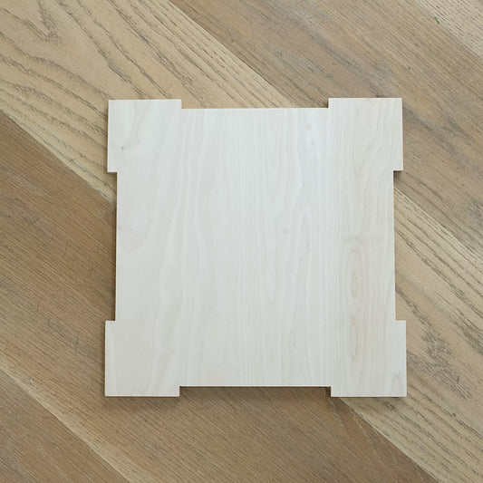 A wooden lid for crate sits in middle of wooden floor.