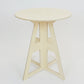 A simple modern pale wooden small table. It has a round top and triangle legs which have slotted together in a cross shape, the base is wider than the top. The top also features four grooves where the legs have slotted into the top.