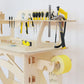 A close up of the pale wooden work bench sits diagonally to the left. Various tools are displayed on the tool rack.