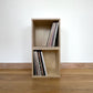 Two simple wooden storage boxes sit front facing, one on top of the other. Both contain records.